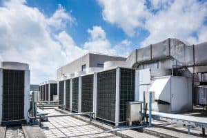 Commercial rooftop HVAC units in front of a blue cloudy sky.