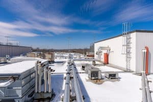 The rooftop of a commercial building with snow on it in front of a clear blue sky