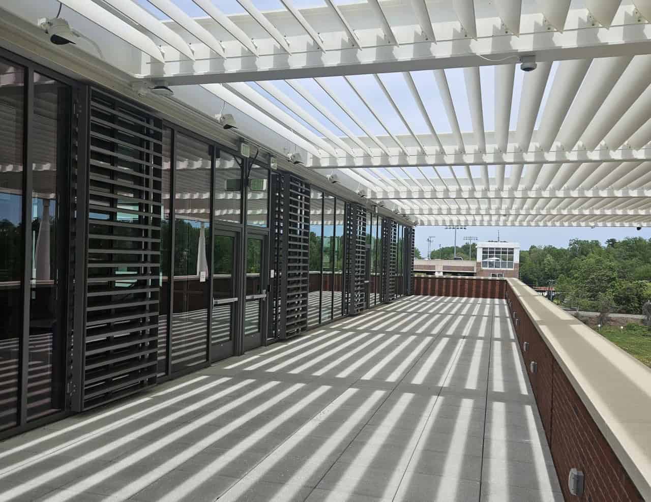 An exterior patio entrance to a building with slatted shading above the patio.