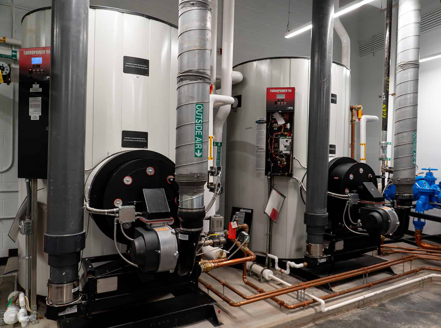 Commercial water heaters and plumbing lines installed in a facility.