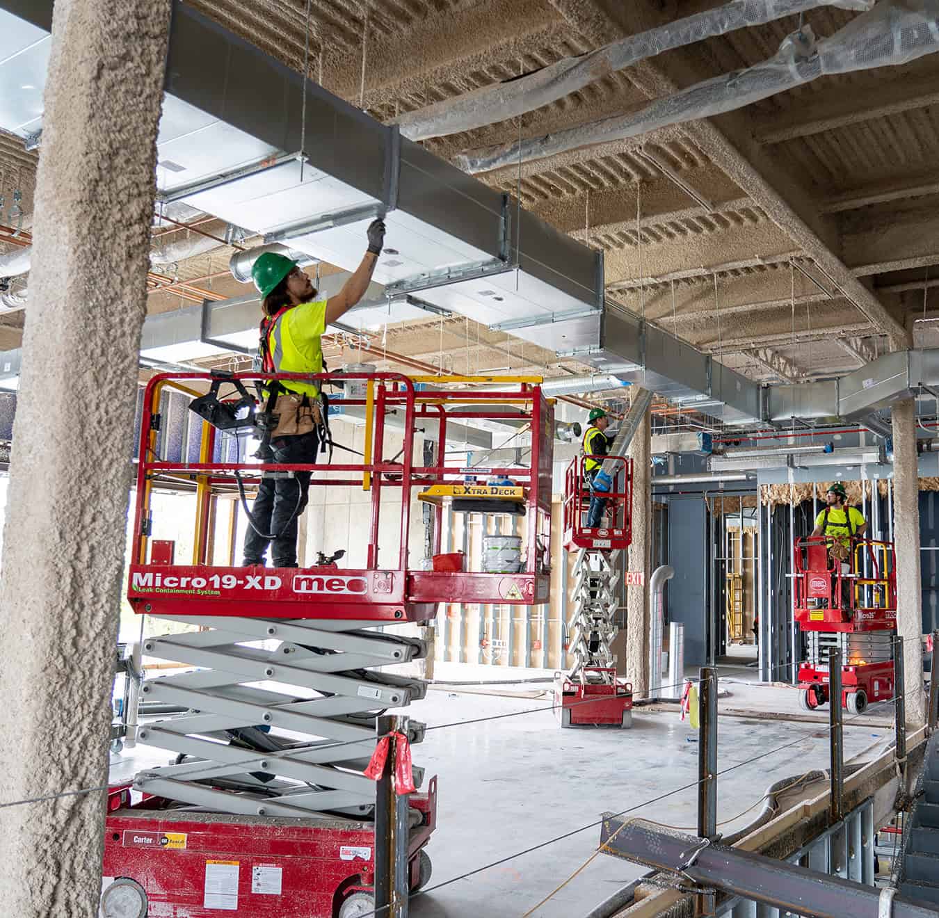RBI employees on scissor lifts installing ductwork in a new build.