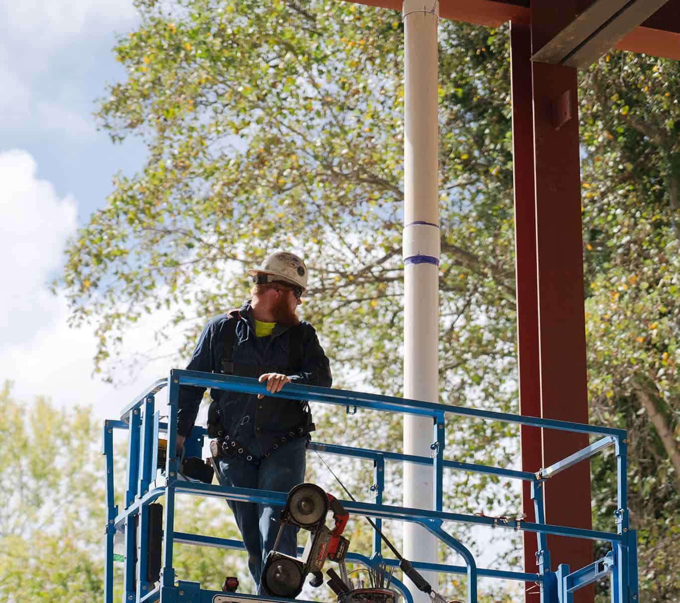 An RBI employee on a lift in front of trees.