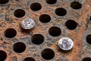 Close up of tubing on a heat exchanger with corrosion on the plate and plugs in some of the tubes