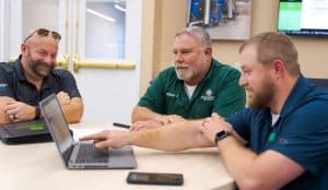 RBI service team members at a table viewing data on a laptop